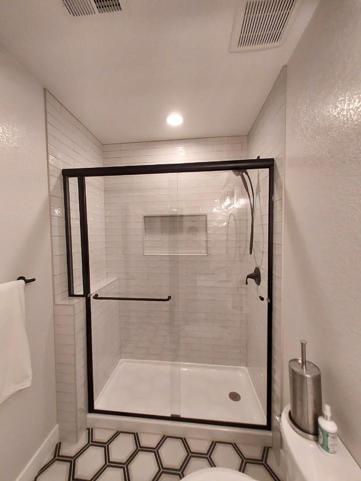 A bathroom with a shower stall and a toilet.