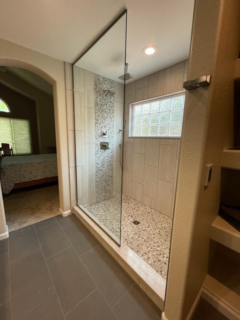 A bathroom with a walk in shower and a window.