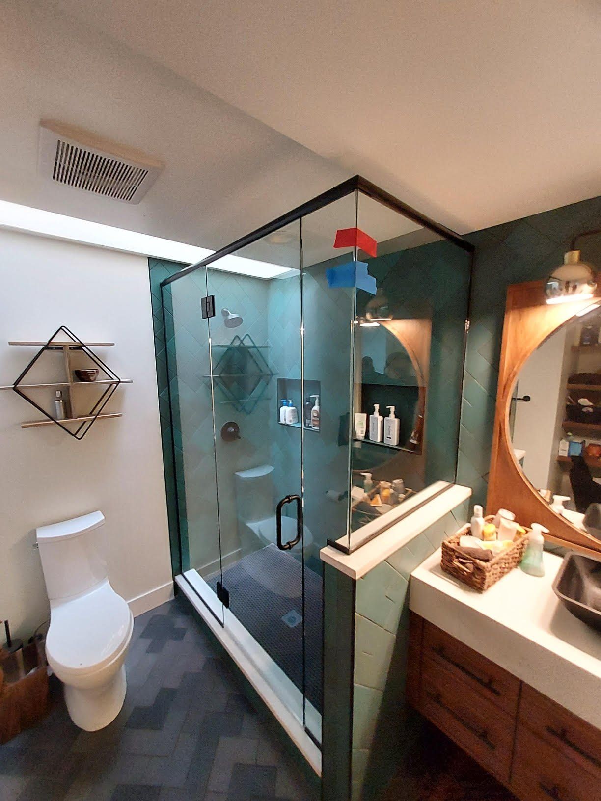 A bathroom with a toilet , sink , shower and mirror.