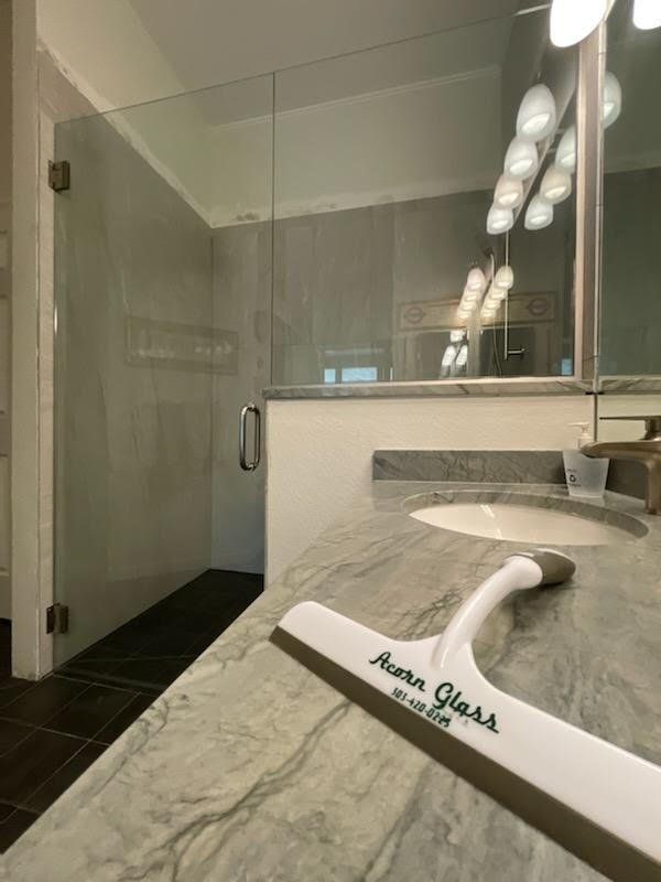 A squeegee is sitting on a bathroom counter next to a sink.