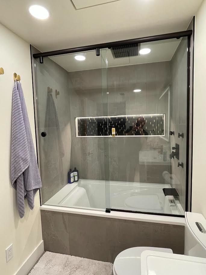 A bathroom with a bathtub , toilet , sink and shower.