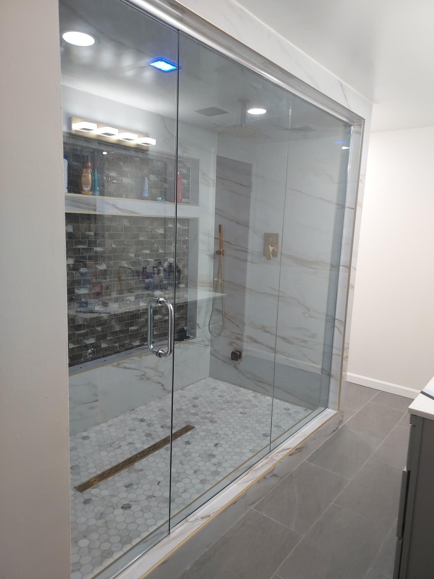 A bathroom with a walk in shower and a glass door.