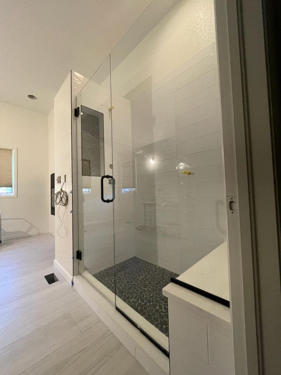 A bathroom with a walk in shower with a glass door
