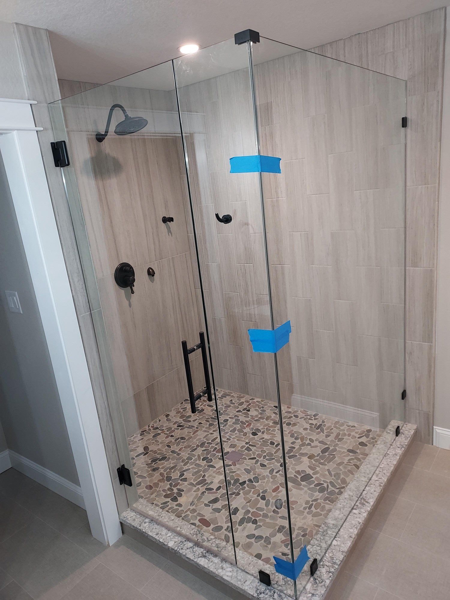 A shower stall with a tiled floor and a shower head in a bathroom.