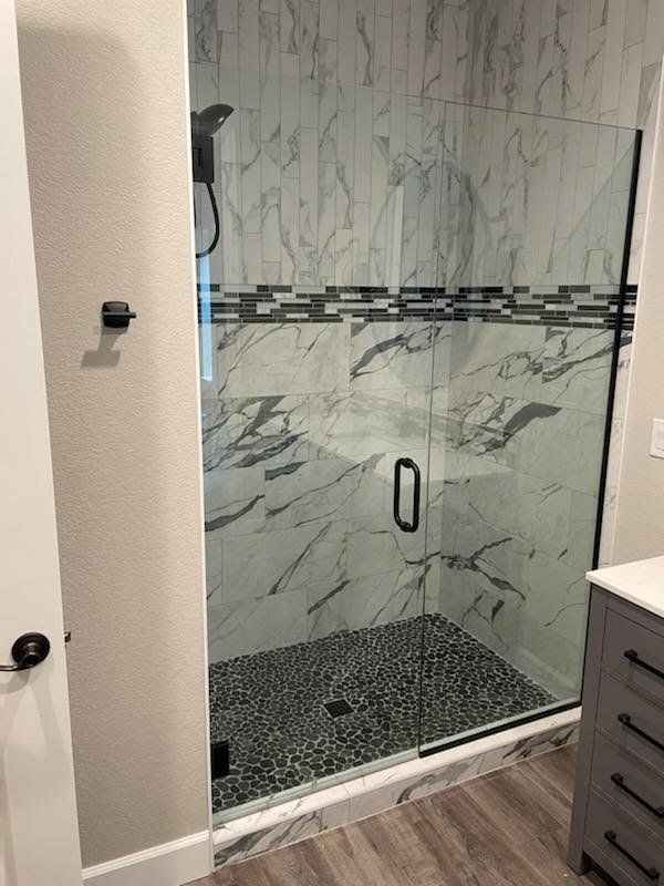 A bathroom with a walk in shower with a glass door.