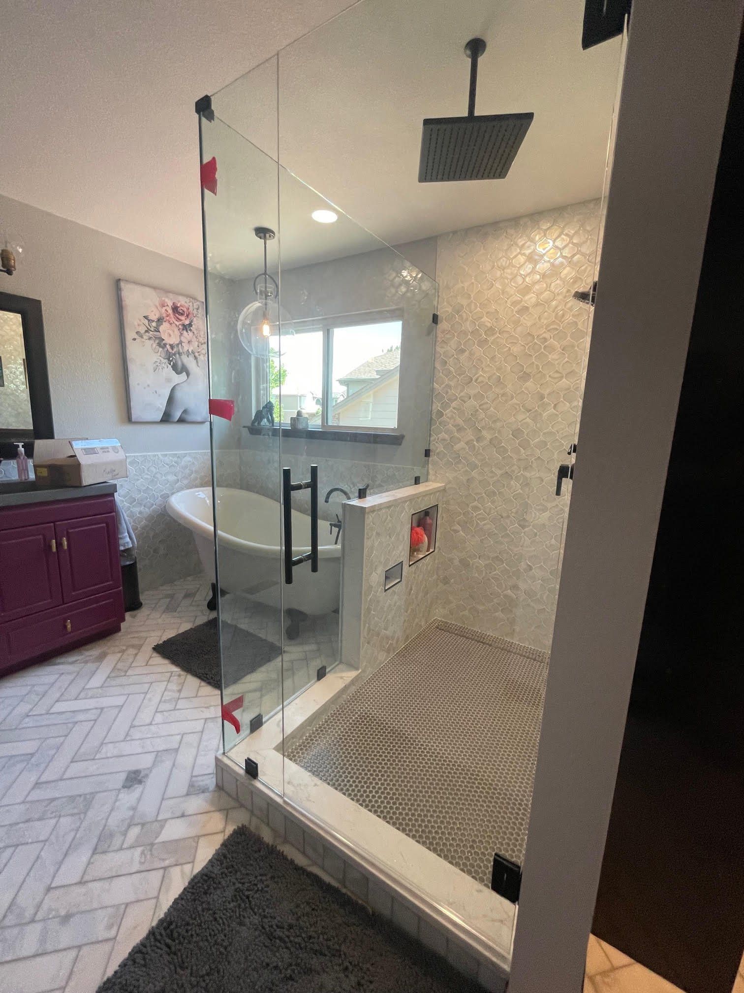 A bathroom with a tub and a shower with a glass door.