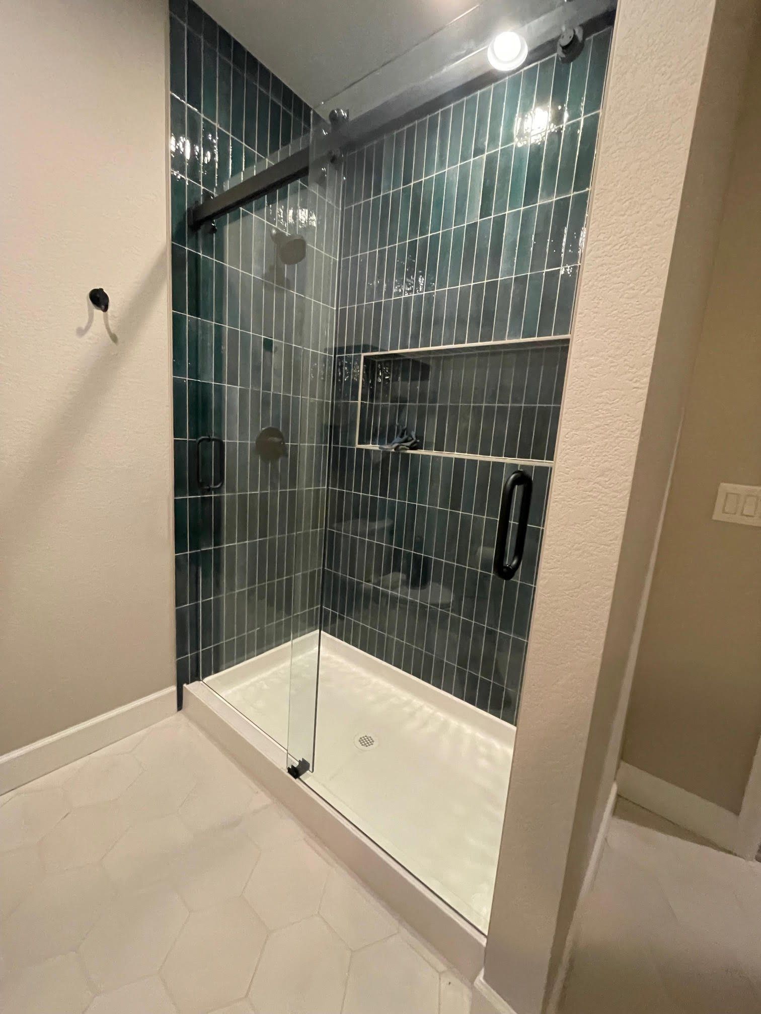 A bathroom with a walk in shower with a glass door.