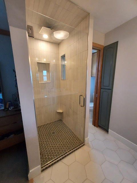 A bathroom with a walk in shower and a glass door.