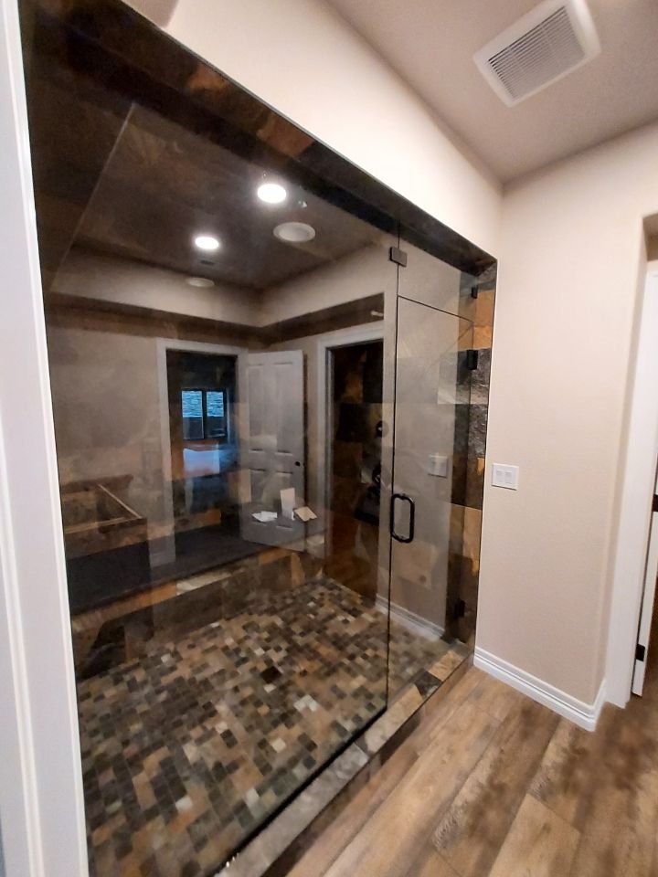 A bathroom with a glass door and a tiled floor.
