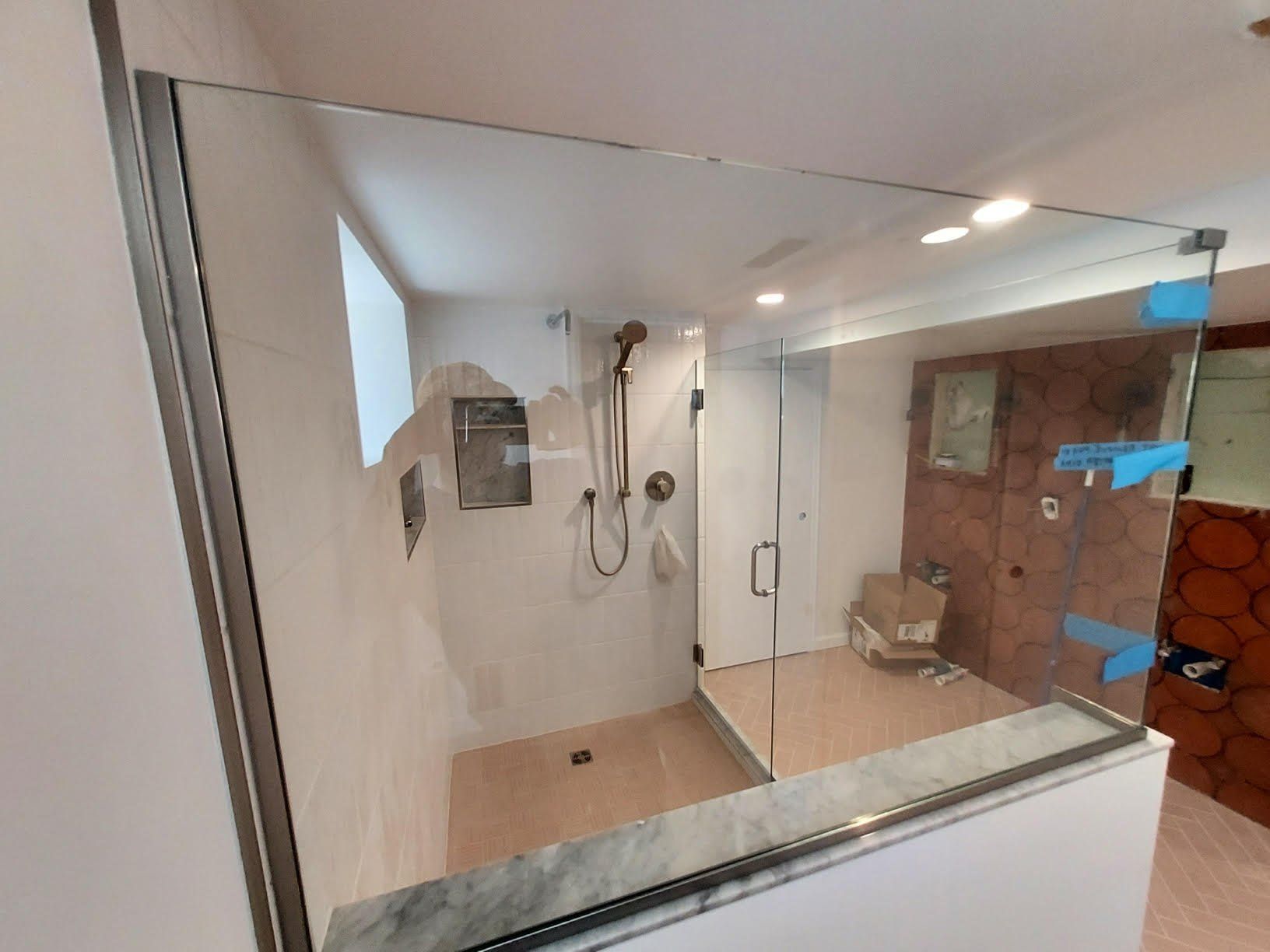 A bathroom with a walk in shower and a glass door.