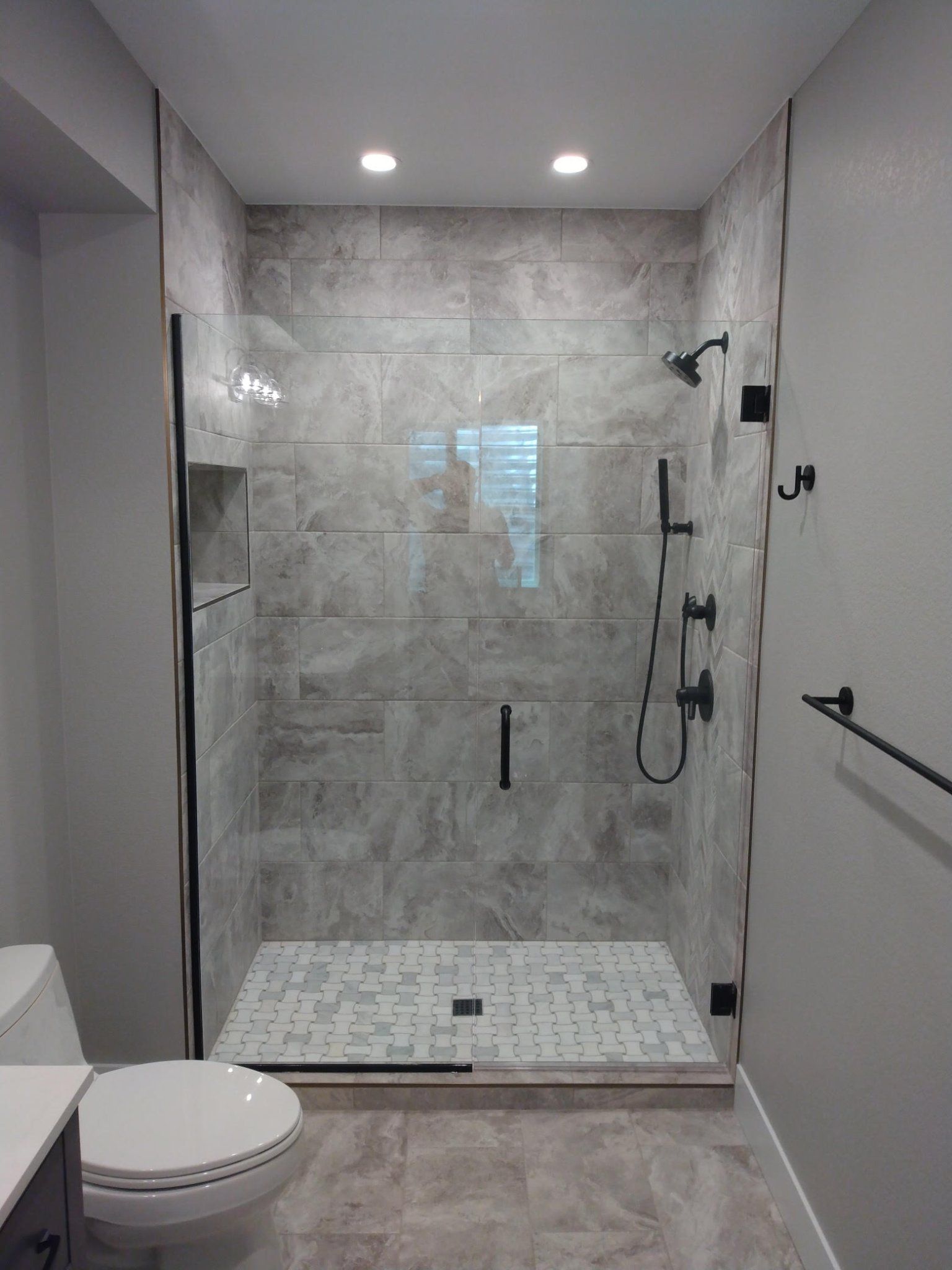 A bathroom with a toilet and a walk in shower with a glass door.