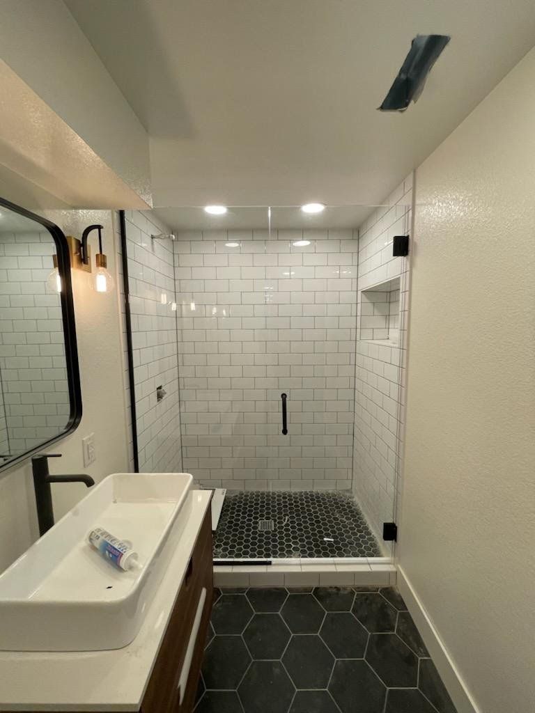 A bathroom with a sink , mirror and shower.