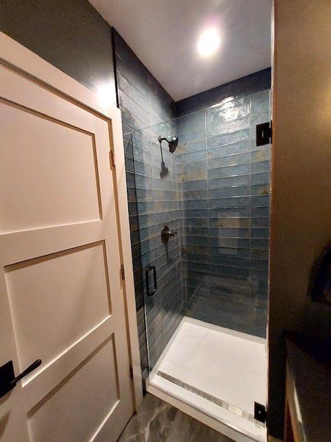 A bathroom with a walk in shower and a white door