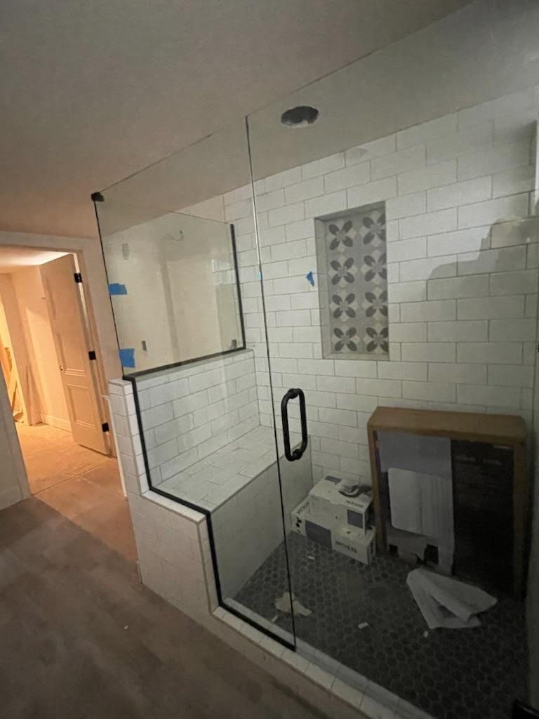 A bathroom with a glass shower door and white tiles.