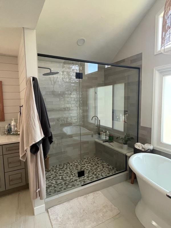A bathroom with a walk in shower , tub , sink and mirror.