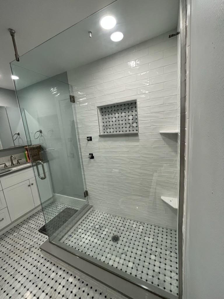 A bathroom with a walk in shower and a sink.