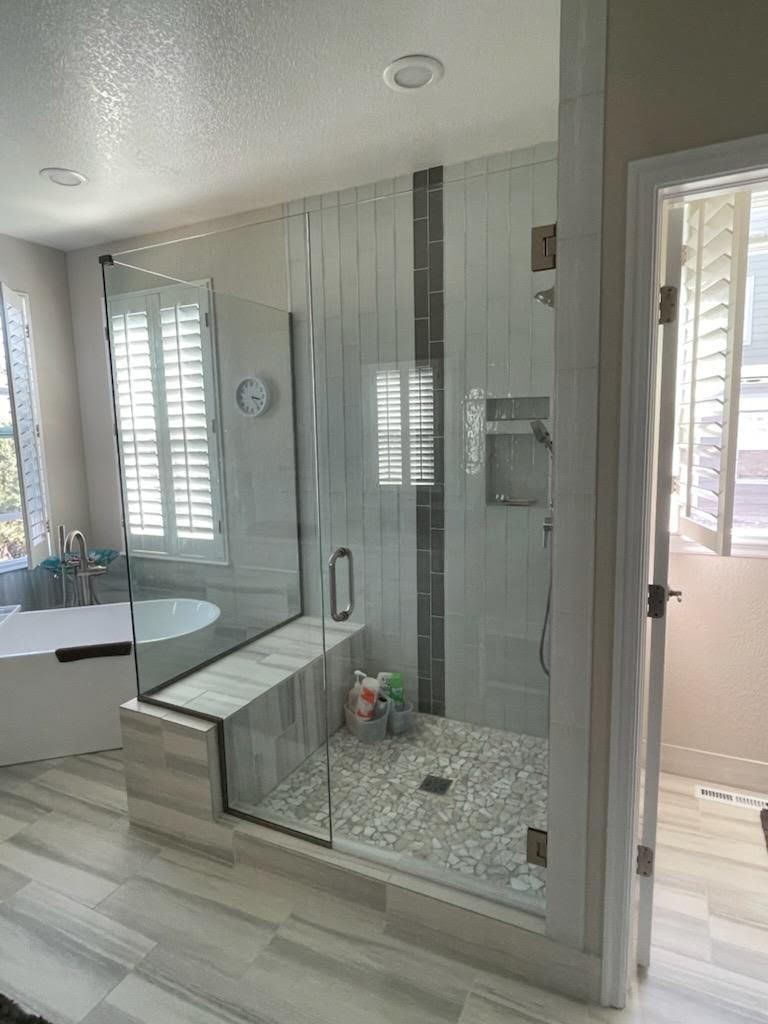 A bathroom with a walk in shower and a tub.