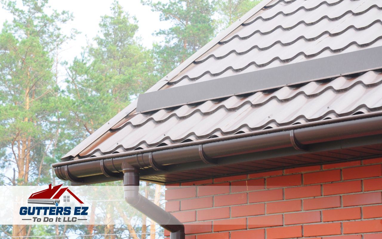 Brown metal roof with gutter and downspout on a house, with trees in the background