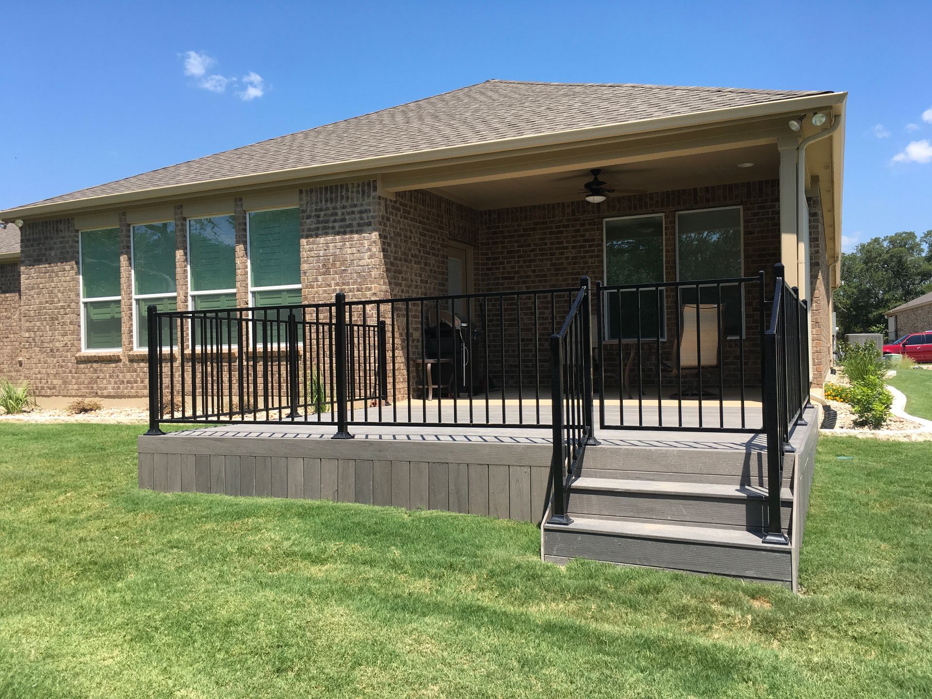 A brick house with a deck and stairs in front of it.