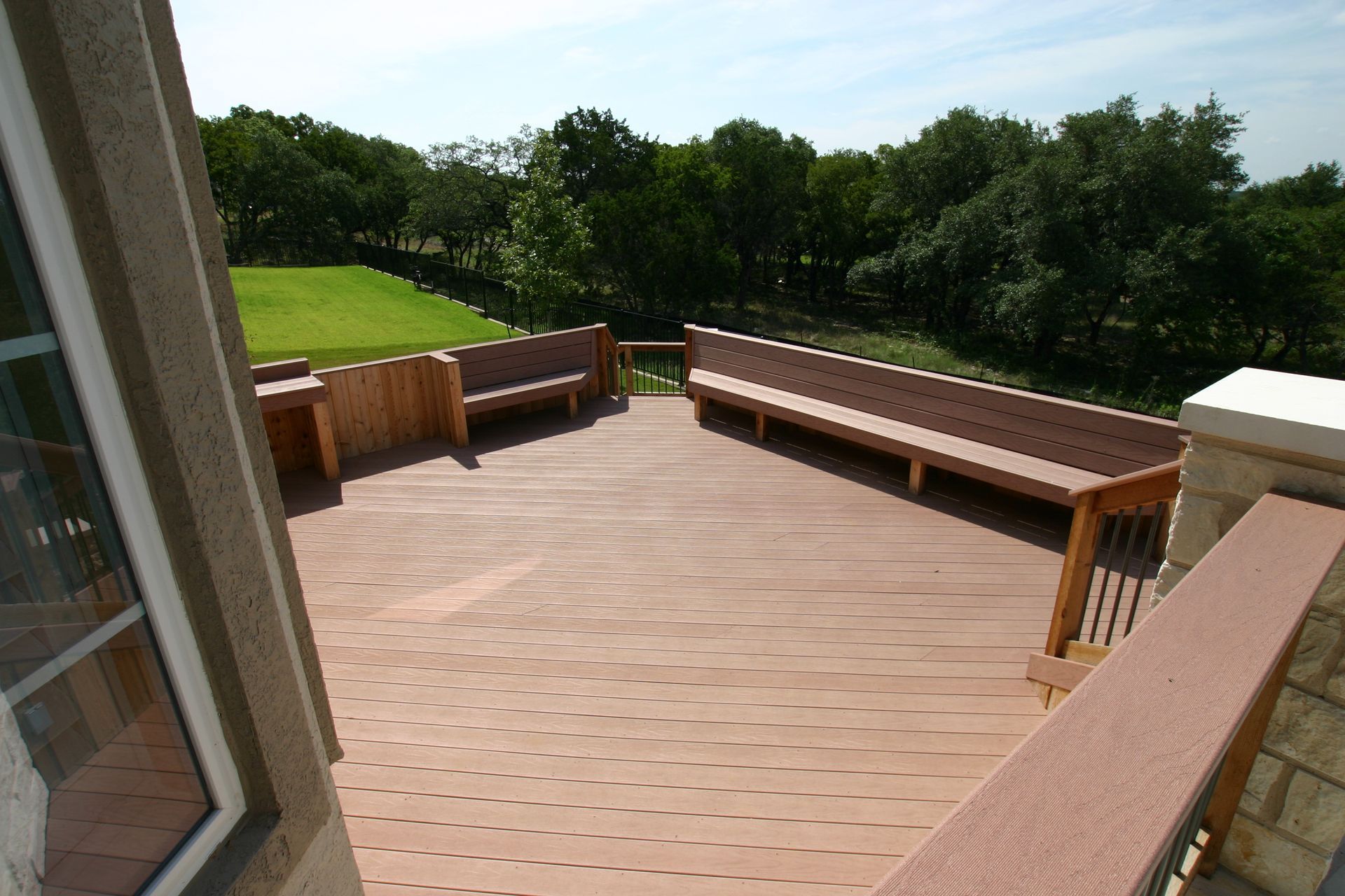 A wooden deck with benches and trees in the background