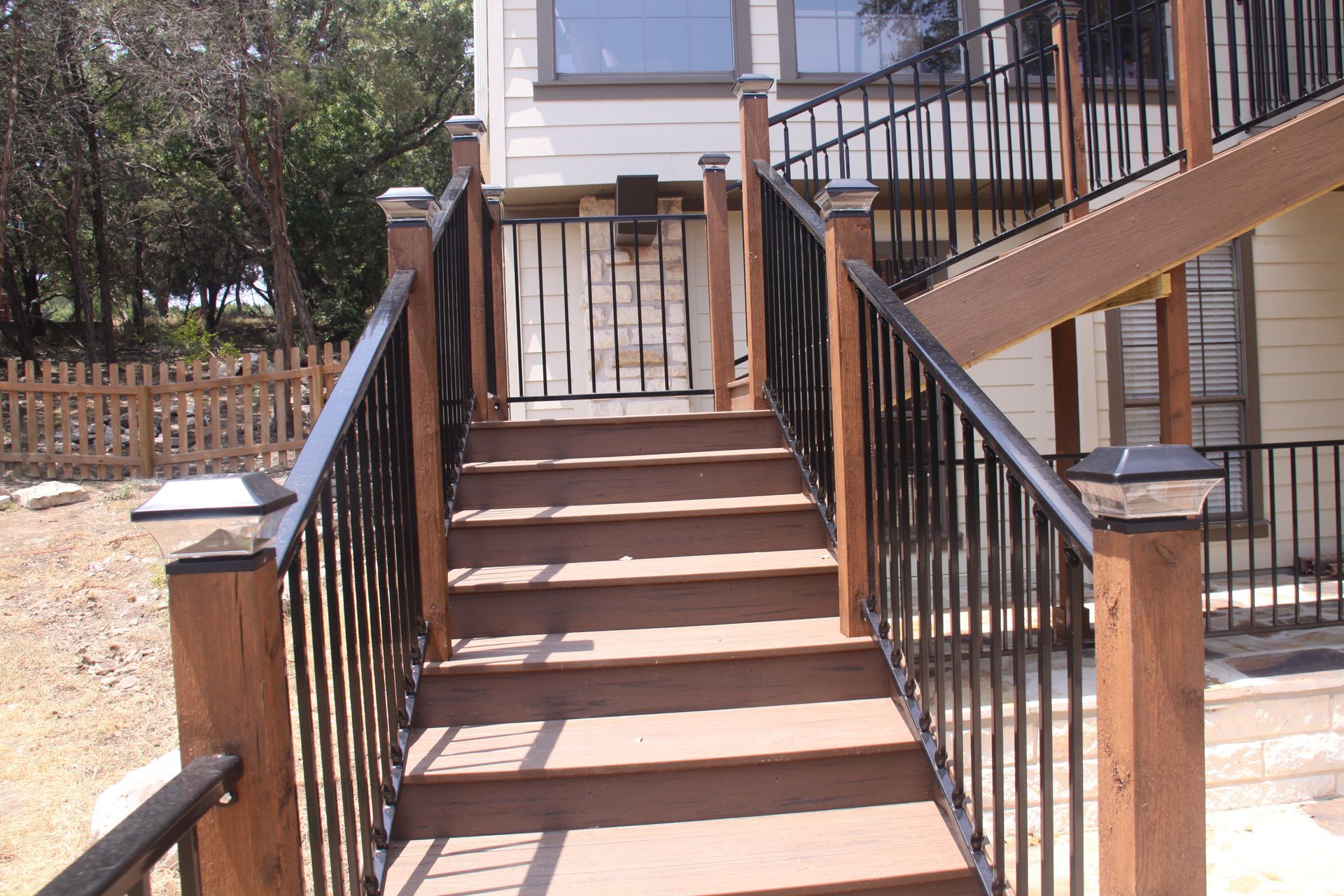A wooden deck with stairs and a black railing
