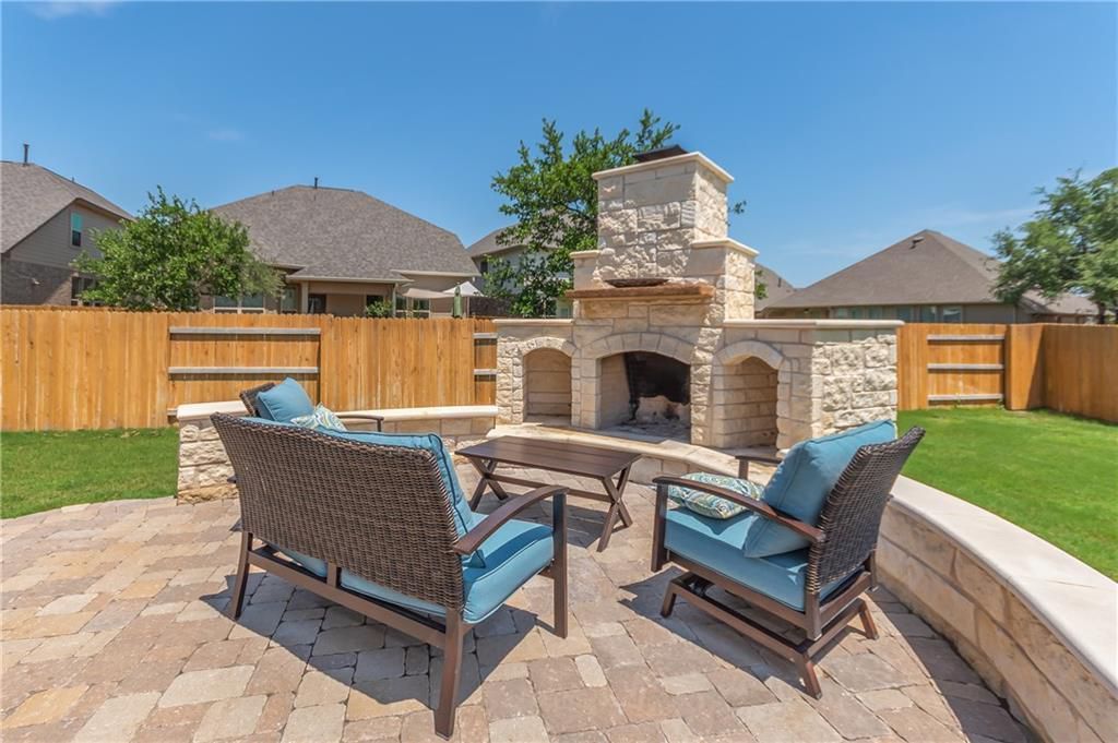 A patio with furniture and a fireplace in the backyard