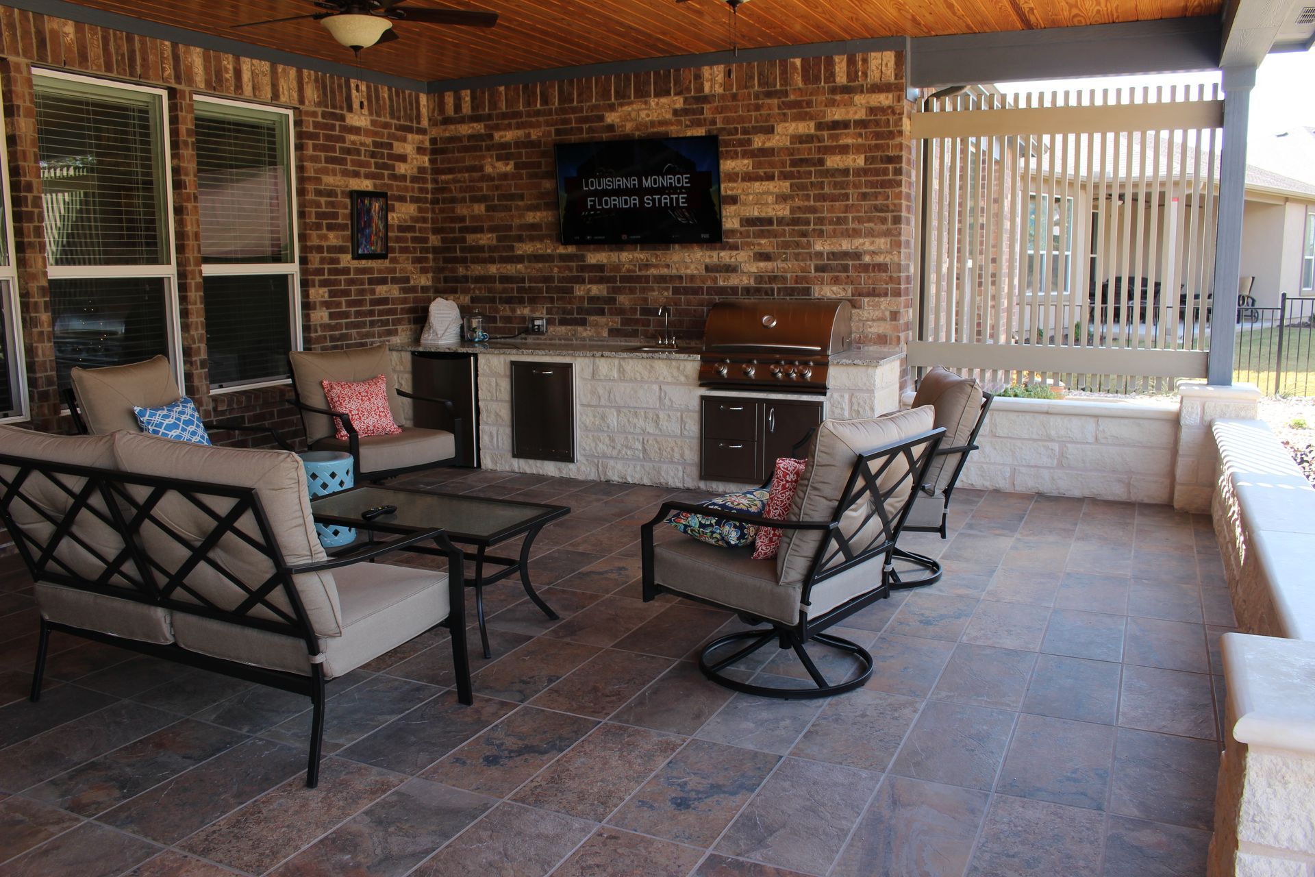 A patio with a couch , chairs , table and television.