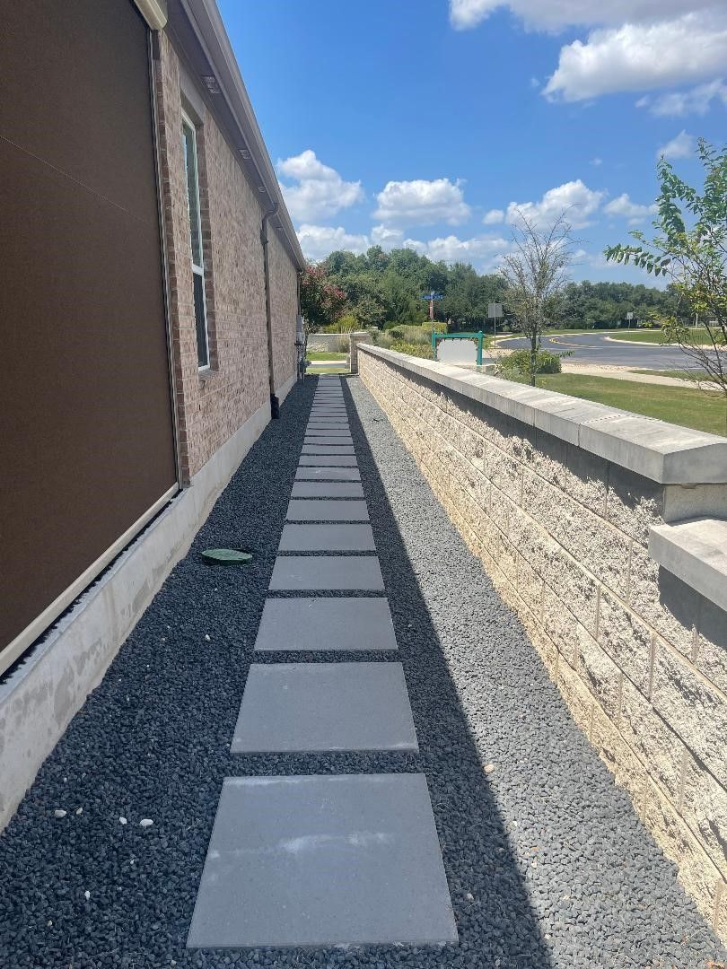 A walkway leading to a house with a stone wall.