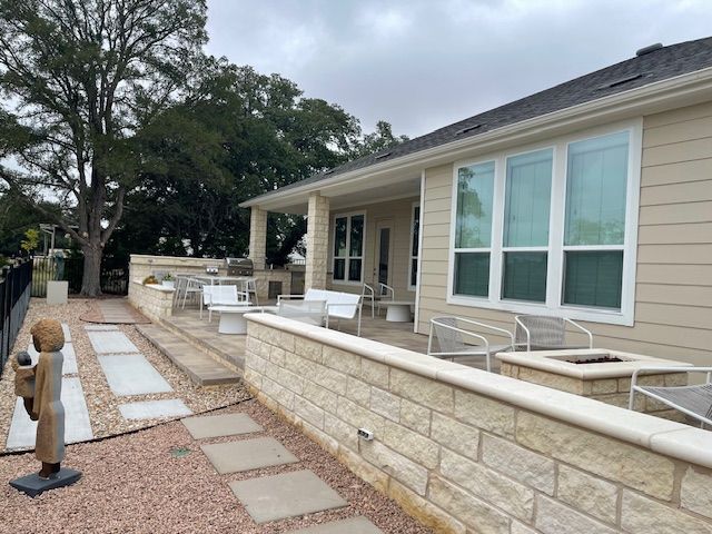 A house with a patio and a brick wall in front of it.