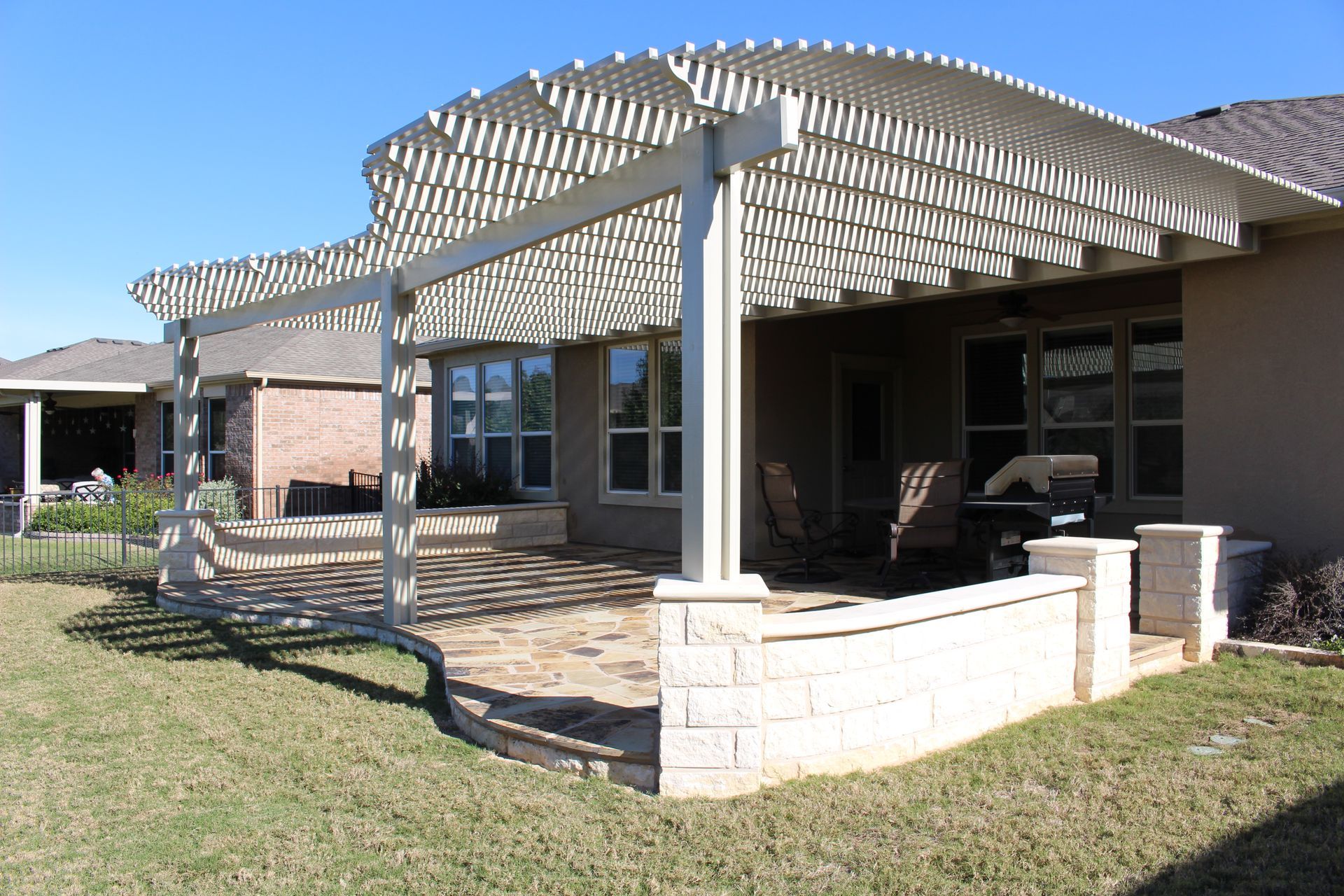 The backyard of a house with a pergola over the patio