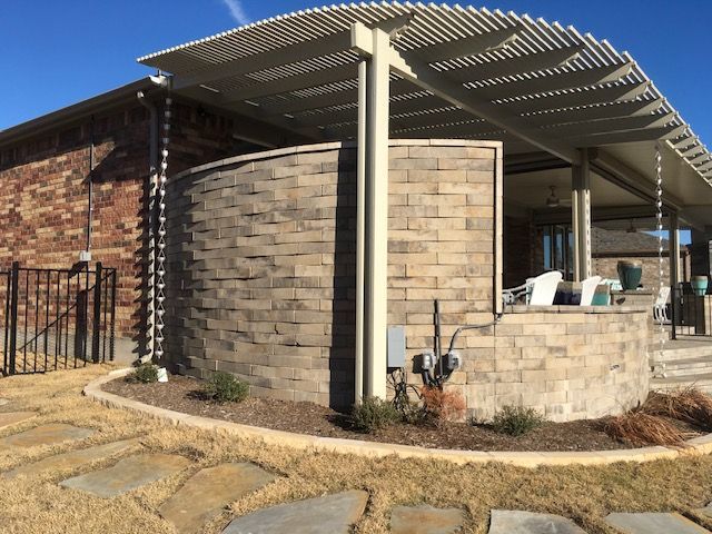 A house with a brick wall and a patio with a pergola