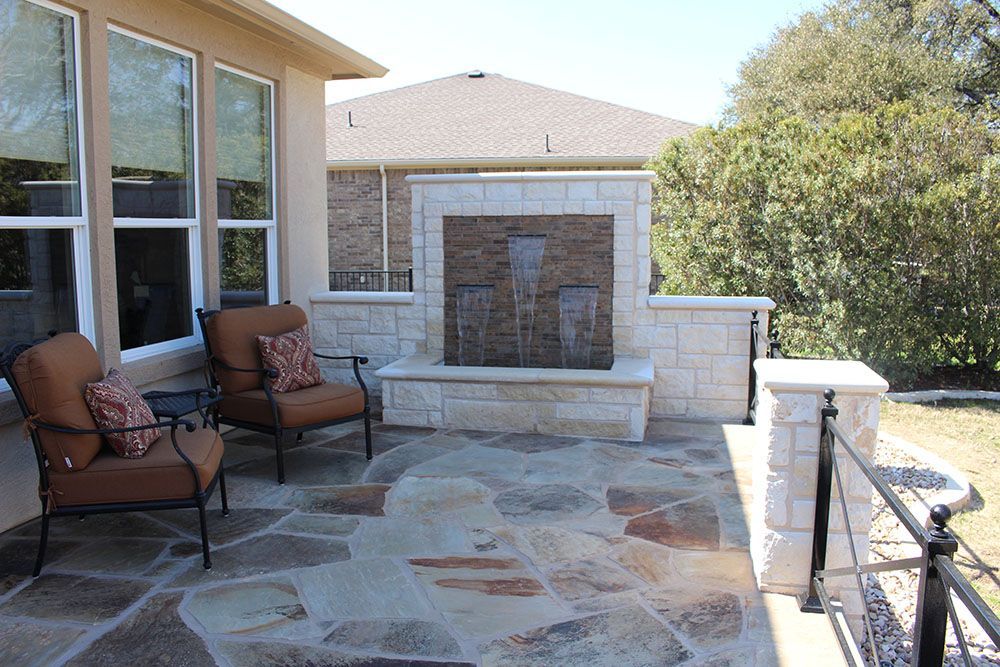 A patio with chairs and a fireplace in the backyard of a house.