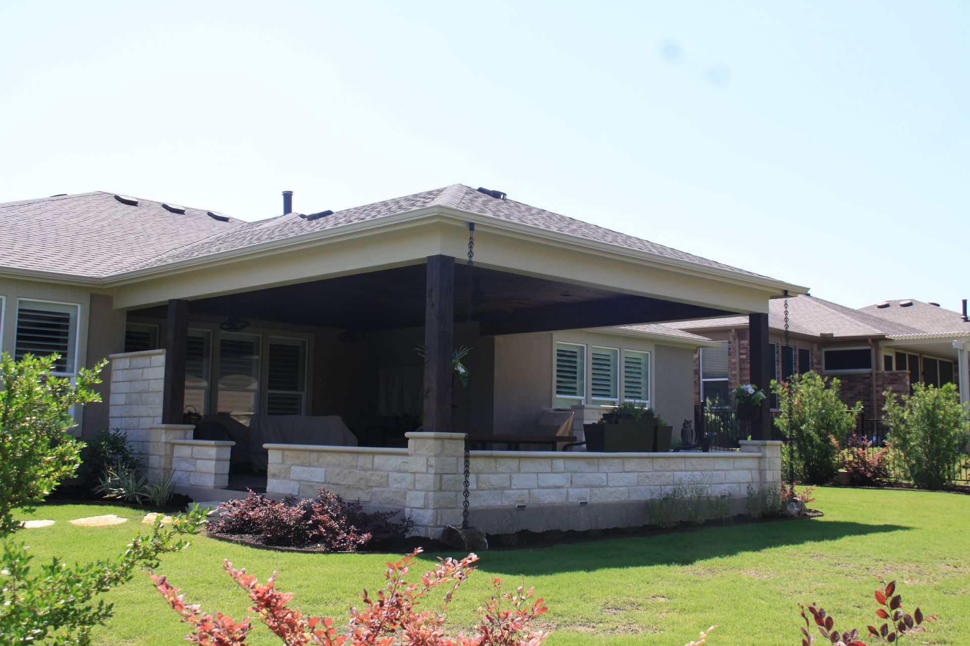 A house with a large porch and a large lawn in front of it.