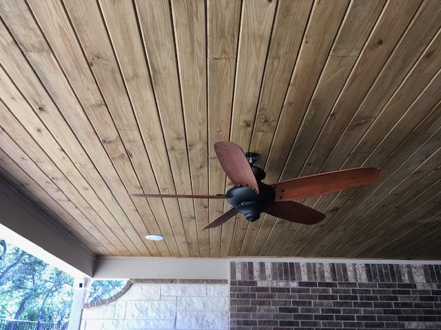 A ceiling fan is hanging from a wooden ceiling