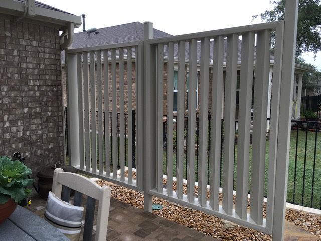 A white fence with a brick building in the background