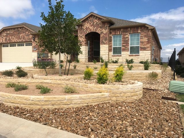 A brick house with a large garage and a stone wall in front of it.