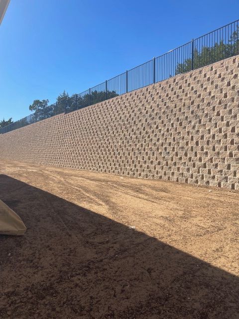 A large brick wall with a fence in the background