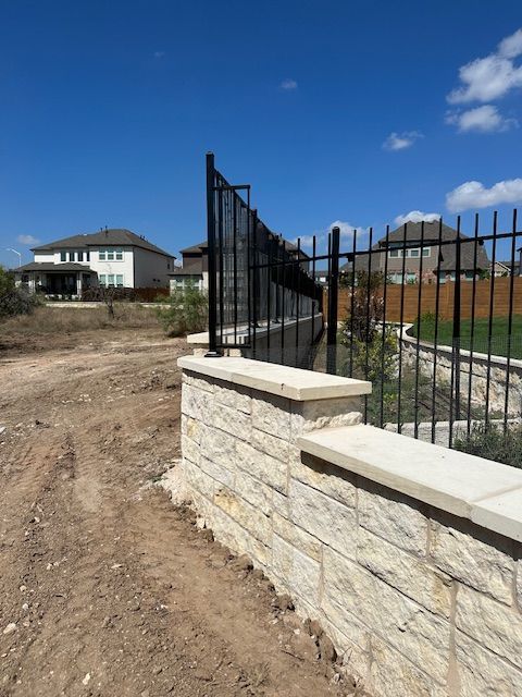 A brick wall with a wrought iron fence surrounding it