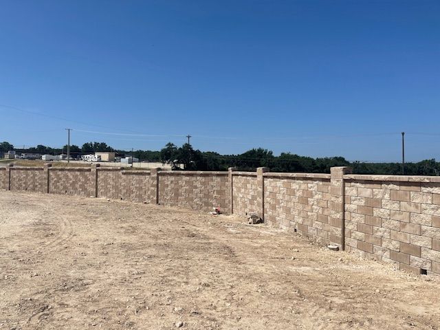 A brick wall is sitting in the middle of a dirt field.