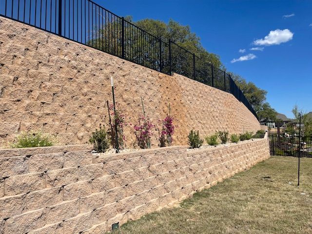 A large brick wall with a metal fence surrounding it.