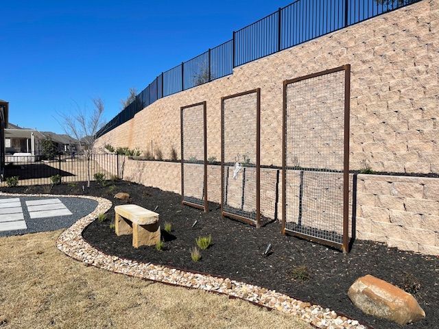 A stone wall with a fence and a bench in front of it.