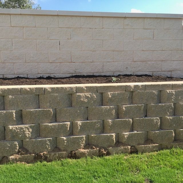 A brick wall surrounds a lush green field