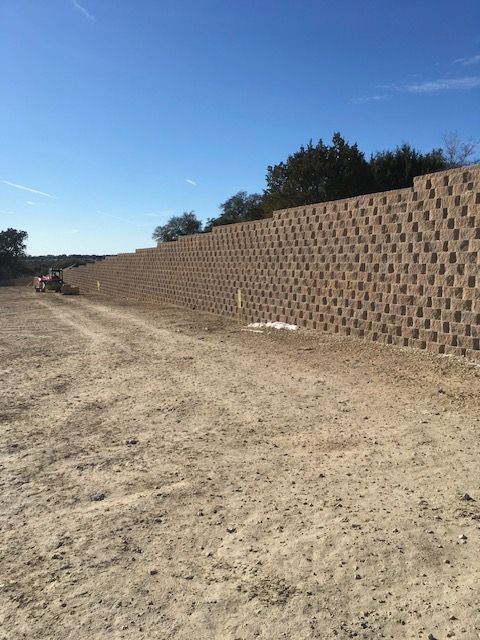A large brick wall is in the middle of a dirt road.