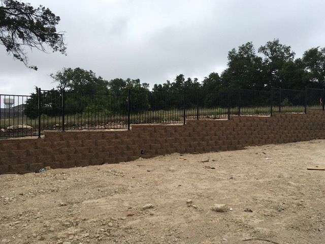A large brick wall with a metal fence surrounding it