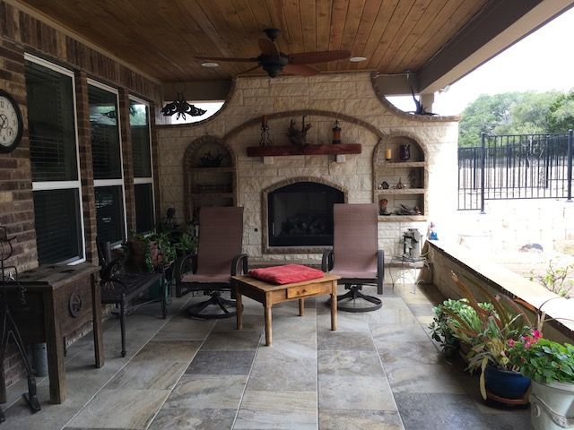 A patio with a fireplace and chairs and a table
