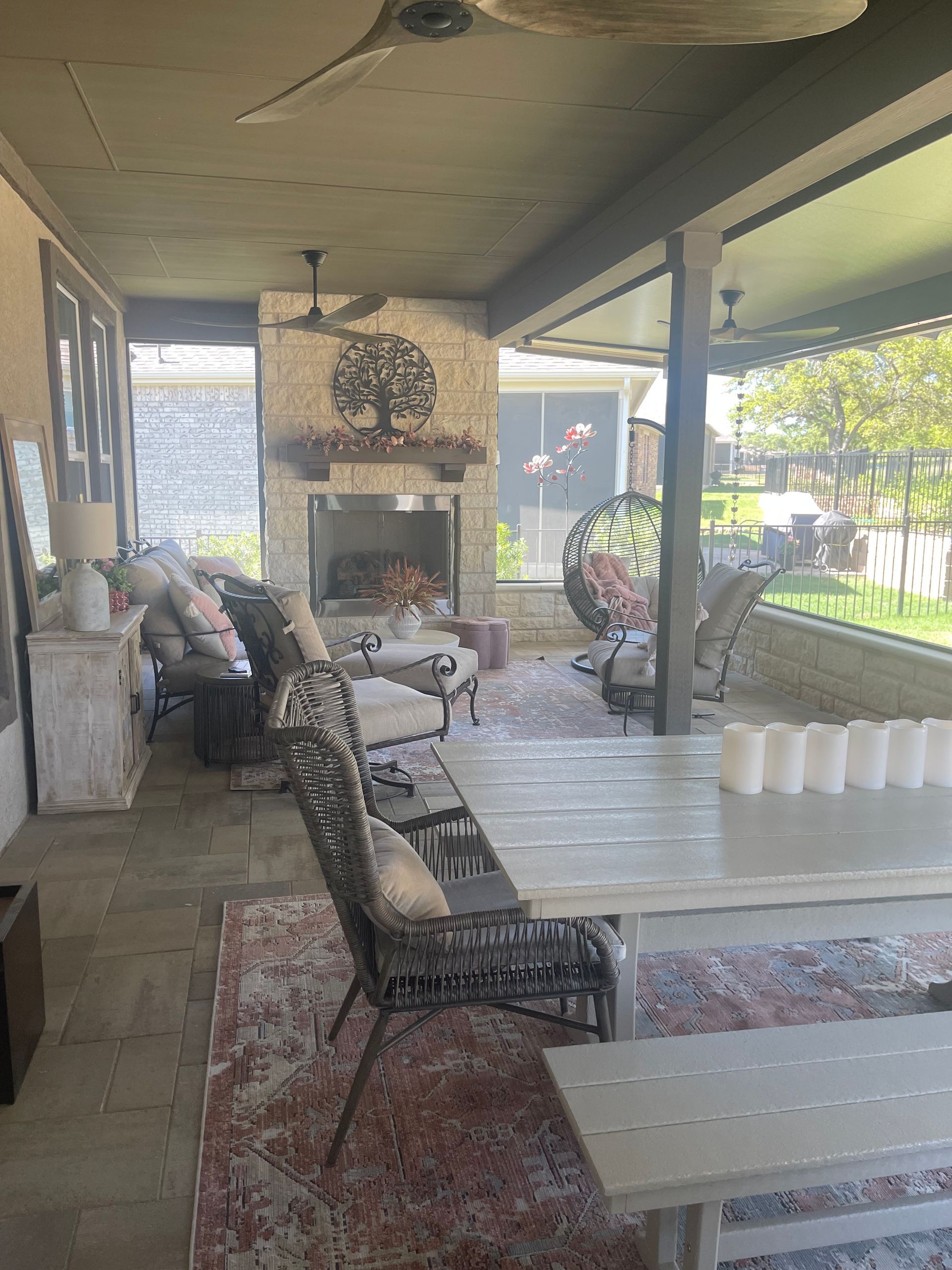 A patio with a table , chairs , a fireplace and a ceiling fan.