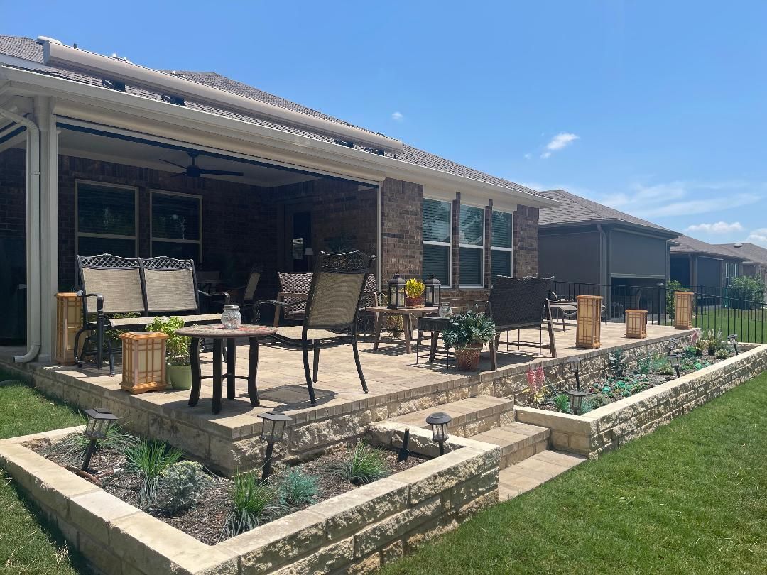 A patio with chairs , tables and umbrellas in front of a house.