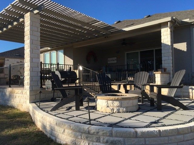 A patio with a fire pit and chairs under a pergola