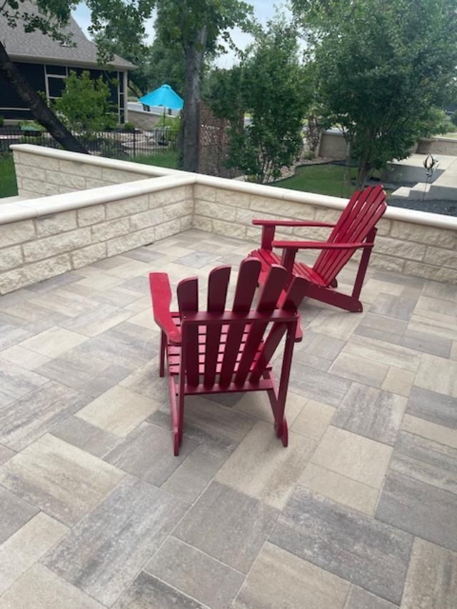 Two red chairs are sitting on a patio next to a brick wall.
