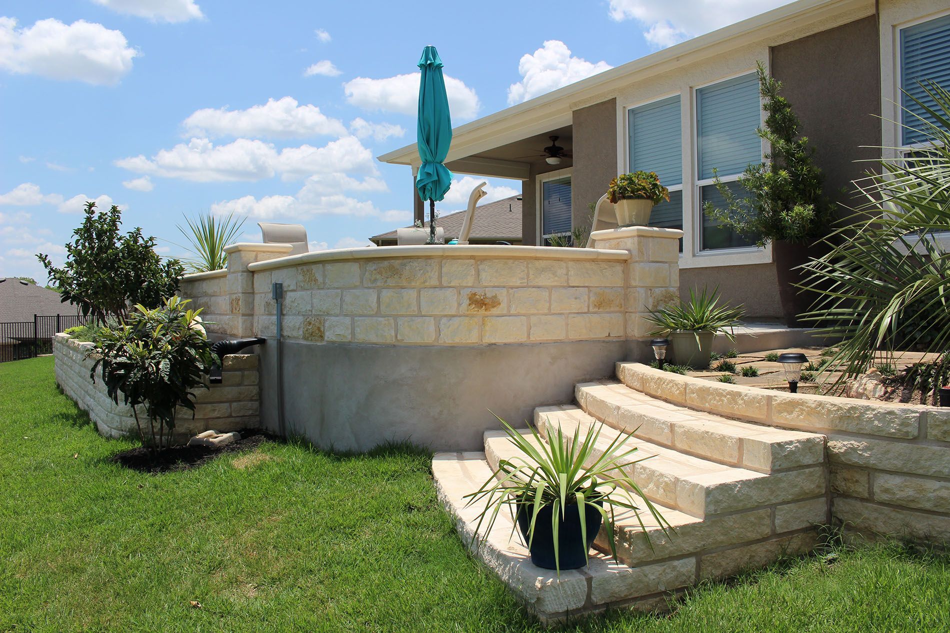 A house with stairs and a blue umbrella in the backyard